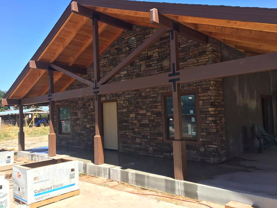 Cultured stone veneer exterior with wood pergola framing by Warrens Masonry