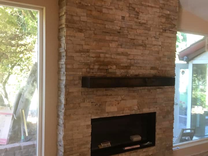 Floor-to-ceiling stacked stone fireplace with linear insert by Warrens Masonry