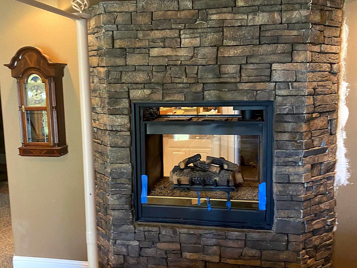 Two-sided corner stone fireplace with gas logs by Warrens Masonry Central Valley CA