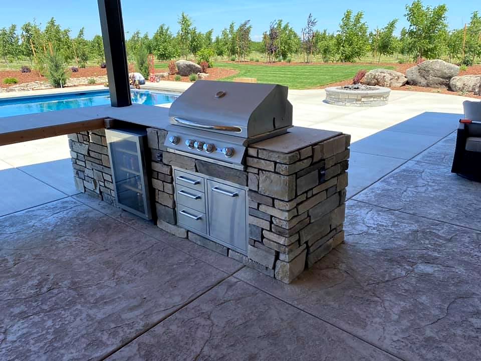 Finished stone BBQ island with pool and fire pit by Warrens Masonry Central Valley CA
